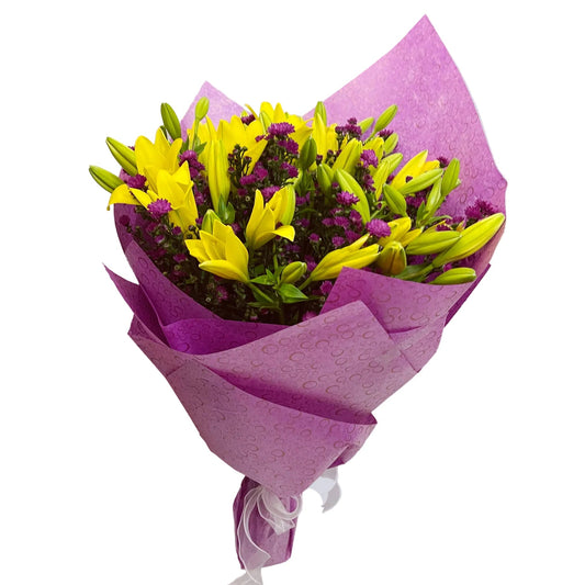 Bouquet of yellow lilies and purple flowers wrapped in purple paper on a light gray background