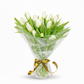 Bouquet of white tulips wrapped in clear plastic with a gold ribbon on a white background